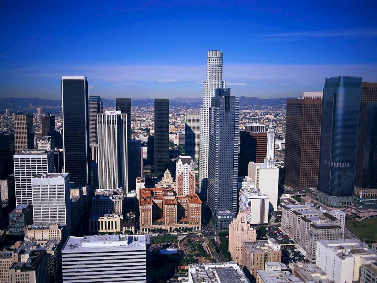 A cityscape featuring numerous skyscrapers under a bright blue sky, suggesting the downtown area of a major metropolitan city.