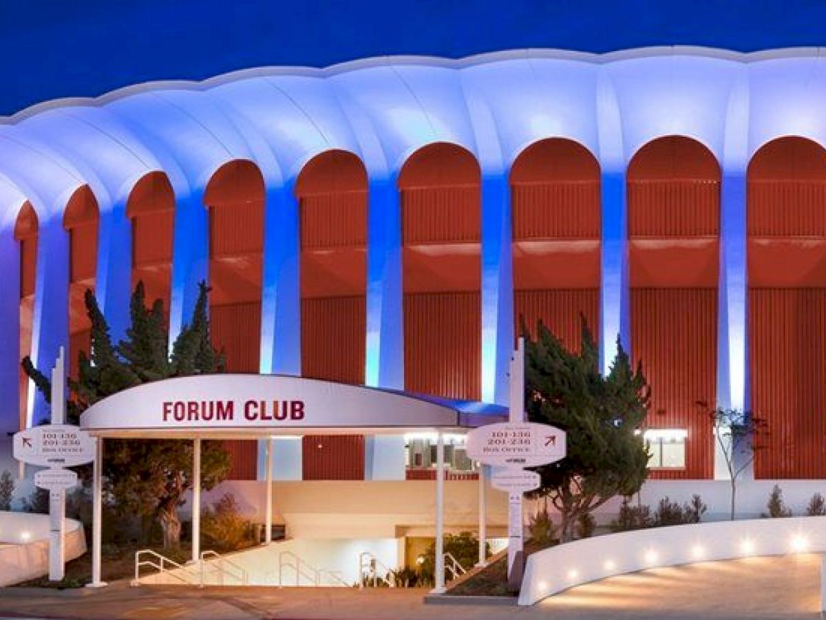 The image shows the exterior of a large, circular building with a sign that reads 